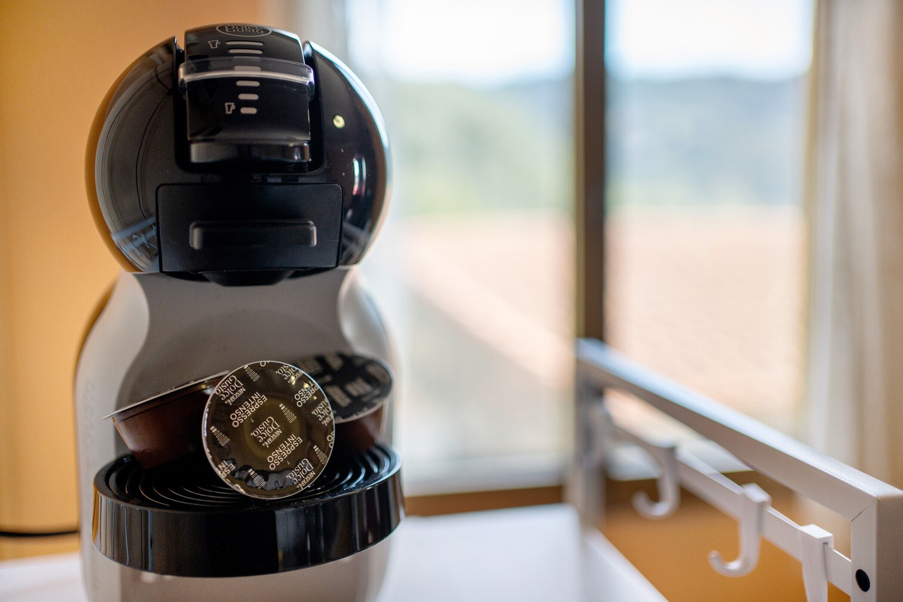Eine Kaffeemaschine mit Tassenablage und Blick aus dem Fenster.