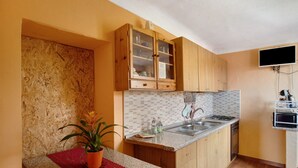 Una cocina con armarios de madera, encimera de granito, un lavamanos, estufa y una planta en maceta.