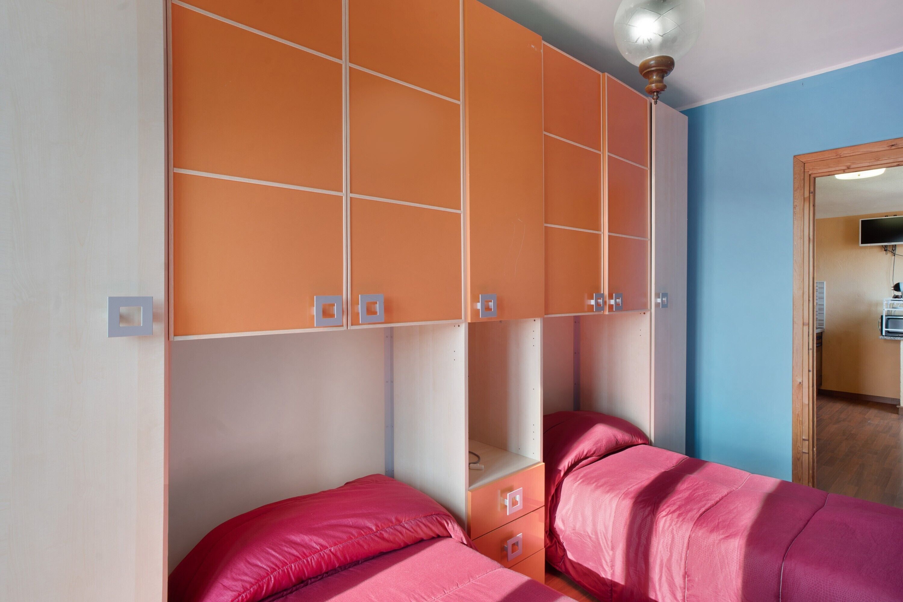 Ein Schlafzimmer mit zwei Betten, einem Kleiderschrank und einem Spiegel.