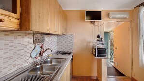 Una cocina con gabinetes de madera, salpicadero de azulejos, un lavamanos de acero inoxidable, una estufa y un horno empotrado.