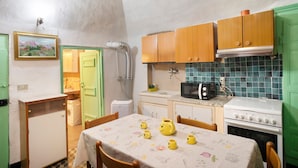 A compact kitchen with a dining table, wooden cabinets, a microwave, and a stove.