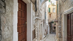 A narrow stone pathway between buildings with wooden doors and shutters.