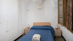 A room with a bed, a nightstand, a lamp, and a window with curtains.