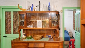 A wooden cabinet with glass doors, a green door, a checkered floor, and a small red stool.
