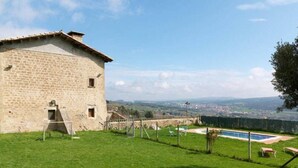 Edificio de piedra con piscina y vistas a un pueblo.