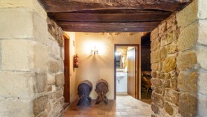Un pasillo con paredes de piedra, techo de madera y suelo de baldosas, además de dos barriles de madera.