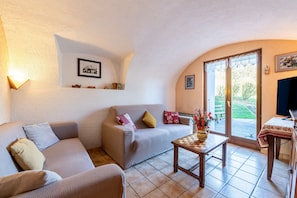 A living room with a sofa, a small table, and a window with a view of the outdoors. - Cottage 'La Sambuy' with Mountain View and Shared Garden (Faverges-Seythenex)