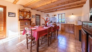 Una cuina amb bigues de fusta, una taula de dinar a punt per a quatre persones i un frigorífic.