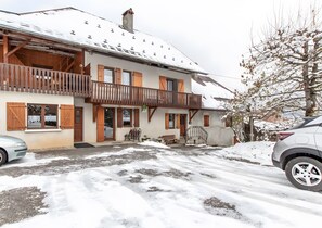 A two-story building with a balcony, wooden shutters, and a snow-covered roof. - Cottage 'La Belle Étoile' with Mountain View and Shared Garden (Faverges-Seythenex)