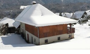A snow-covered wooden house with a balcony, surrounded by a snowy landscape. - Gîte 'La Belle Étoile' with Mountain View and Private Garden (Faverges-Seythenex)