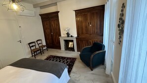 Une pièce avec un lit, une cheminée, un fauteuil bleu et des meubles en bois.