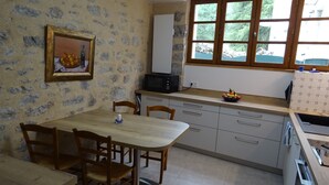 Une cuisine équipée d’une table à manger, de chaises, d’un four à micro-ondes et d’une fenêtre donnant sur un espace verdoyant.