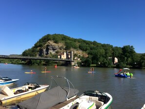 A river with boats, a bridge, and a forested hill.