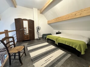 Une chambre à coucher avec un lit, une chaise, une armoire, un ventilateur et un tapis à rayures.