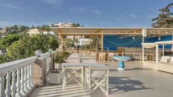 A rooftop terrace with outdoor seating, a pool table, and a view of the surrounding buildings.