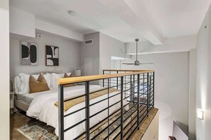 Lofted bedroom with chic railing, modern decor, and a view overlooking the living area. - CBD OTR Gym, Pool, Free Parking, Steps to Stadiums (Cincinnati)