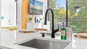 A modern kitchen with a large window, a black faucet, and two soap dispensers on the counter. - Luxury 1BD Gym, Rooftop, Street Parking by DT, UMN (Minneapolis)