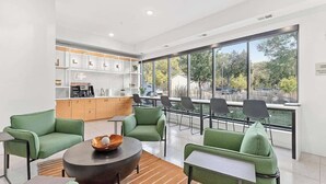 A modern lounge area with green seating, a coffee station, and large windows offering a view of the outdoors. - Luxury 1BD Gym, Rooftop, Street Parking by DT, UMN (Minneapolis)