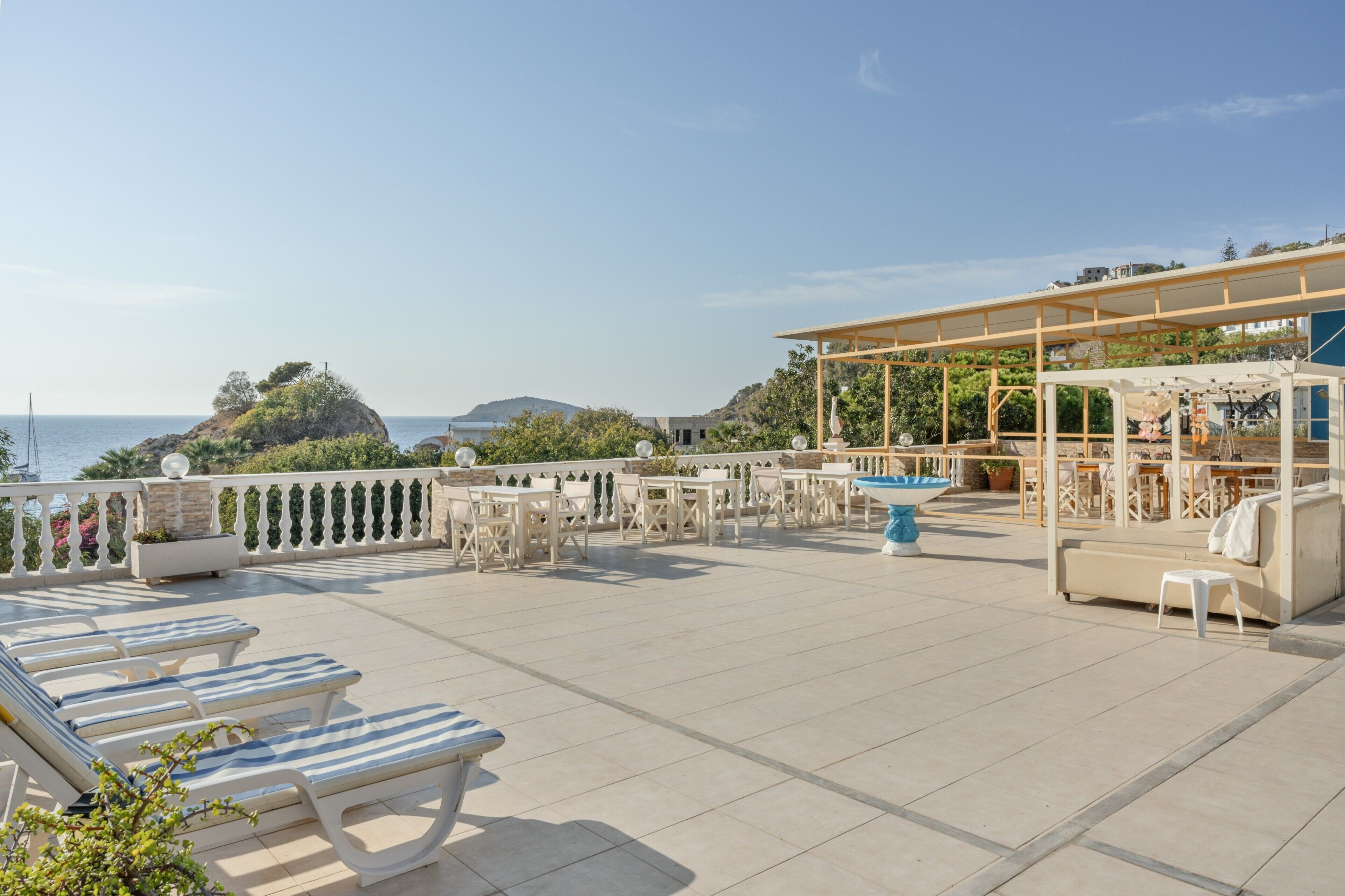 Une terrasse sur le toit avec des chaises longues, une piscine et un espace salon abrité.