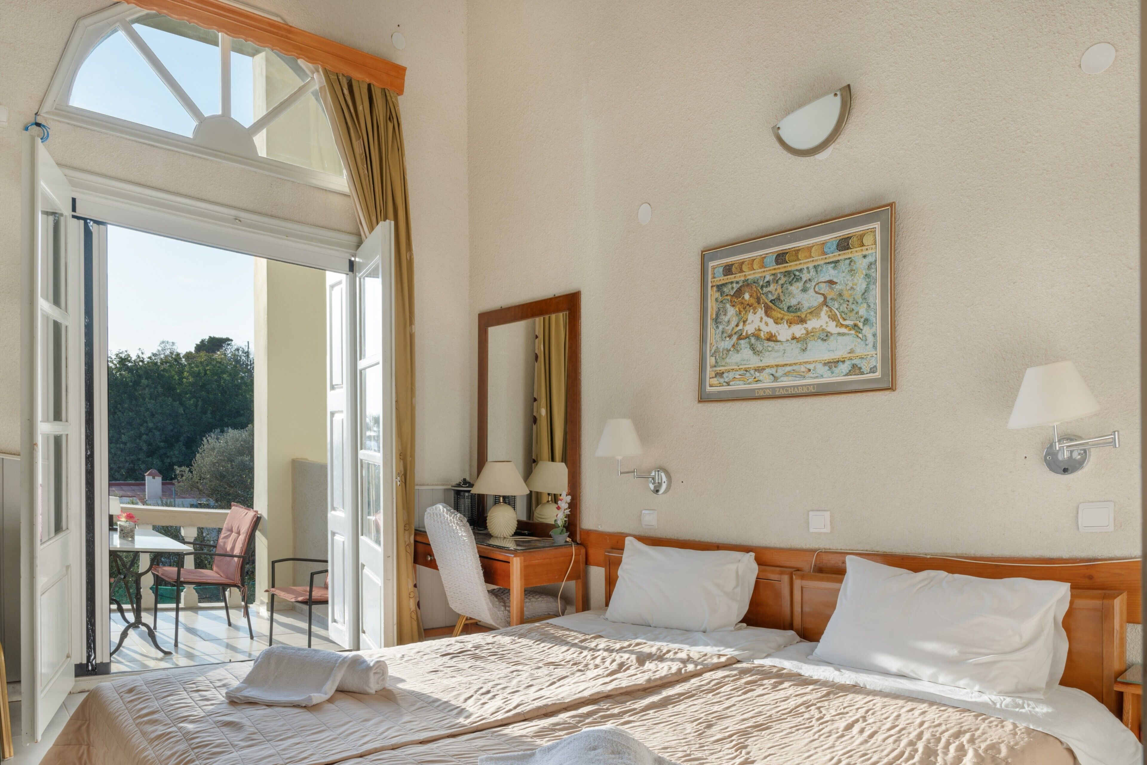 Een hotelkamer met een bed, een bureau, een stoel, een raam en een schilderij aan de muur.