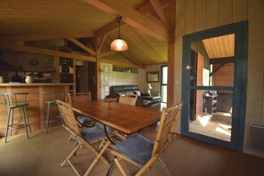 Cozy interior with a high ceiling, wooden dining table, and sliding glass door to an outdoor deck.
