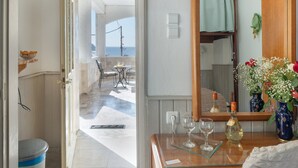 A room with a wooden vanity, a mirror, a vase with flowers, and a view of the sea through an open door. - Apartment 'Double Studio No 1' with Sea View, Wi-Fi and Air Conditioning (Panormos Kalymnos)