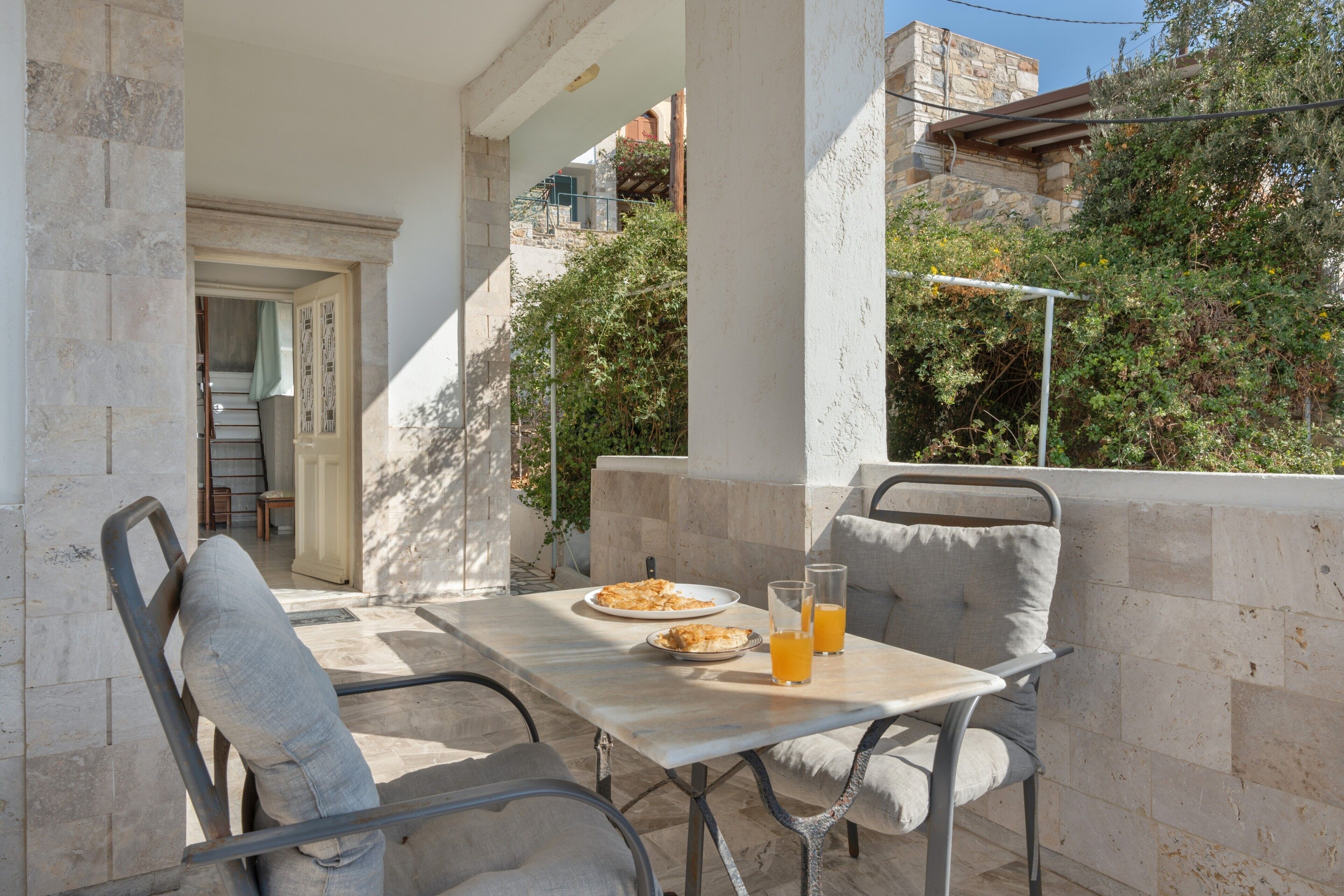 Un patio al aire libre con una mesa, sillas y un vaso de jugo de naranja.