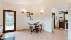 Ein Essbereich mit rundem Tisch und Stühlen, eine Küche mit Schränken und Spüle sowie eine Tür, die auf einen Balkon führt.