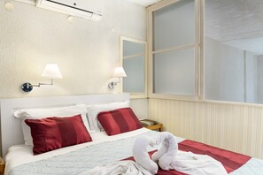 Une chambre d’hôtel avec un lit, deux lampes fixées au mur, une fenêtre et un radiateur.