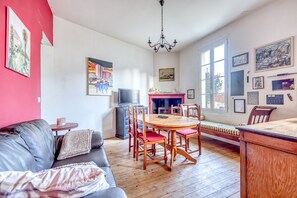 Un salon comprenant un canapé, une table à manger avec des chaises, un téléviseur et des œuvres d’art accrochées aux murs.