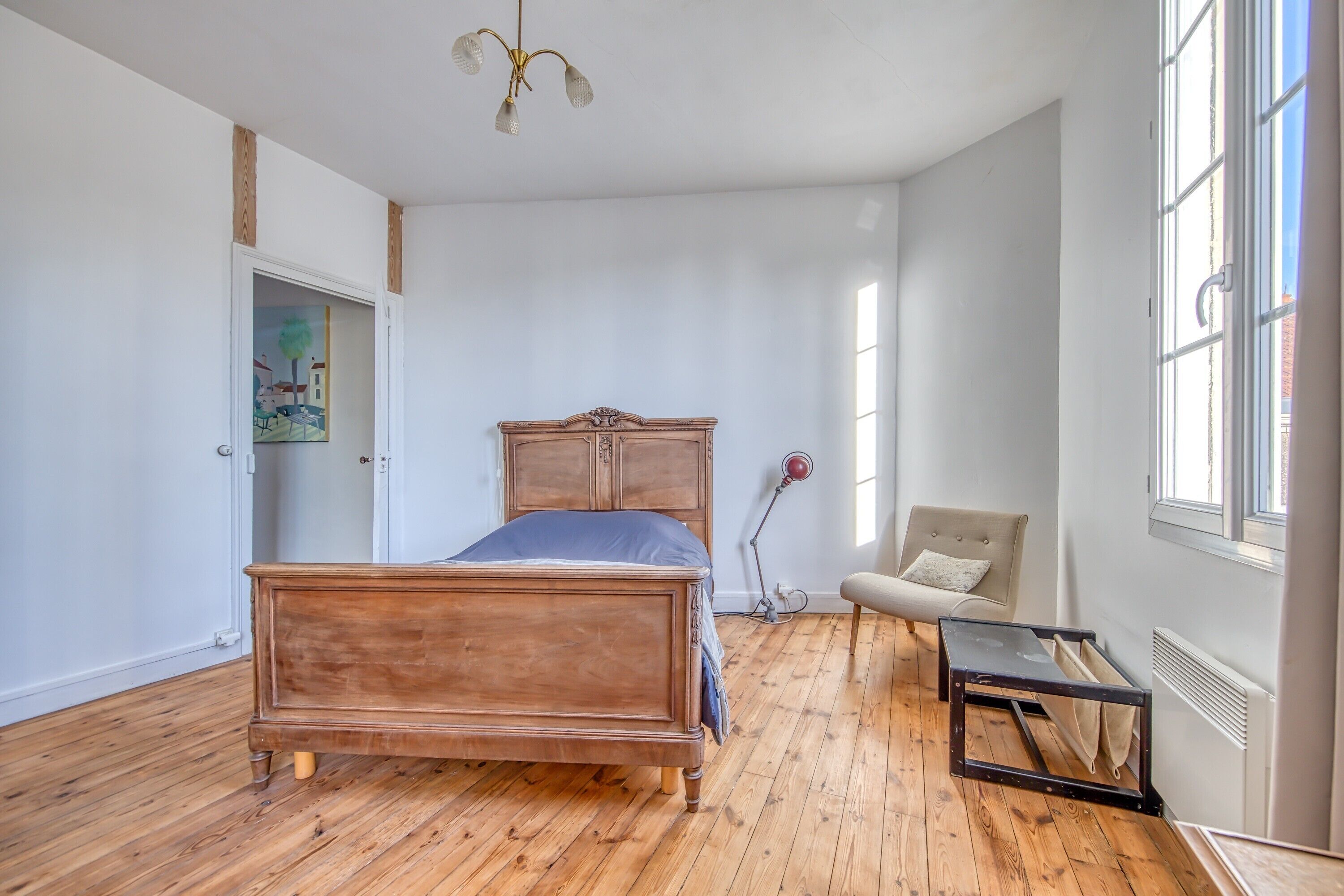 Une chambre à coucher avec un lit en bois, une chaise, un bureau et une fenêtre.