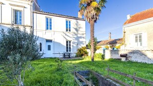Un bâtiment blanc avec un toit recouvert de tuiles, un palmier et une clôture en bois.