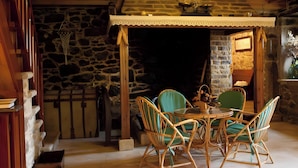 Habitación con paredes de piedra, muebles de mimbre y una mesa.