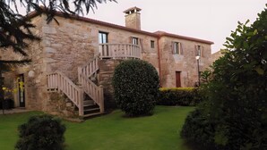 Un edificio de piedra con una escalera, una chimenea y un césped bien cuidado.