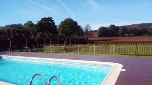 Una piscina con cerca de madera y árboles al fondo.