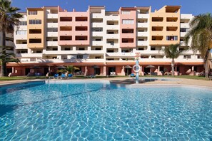 Un hôtel doté d’une piscine, de plusieurs balcons et de palmiers.