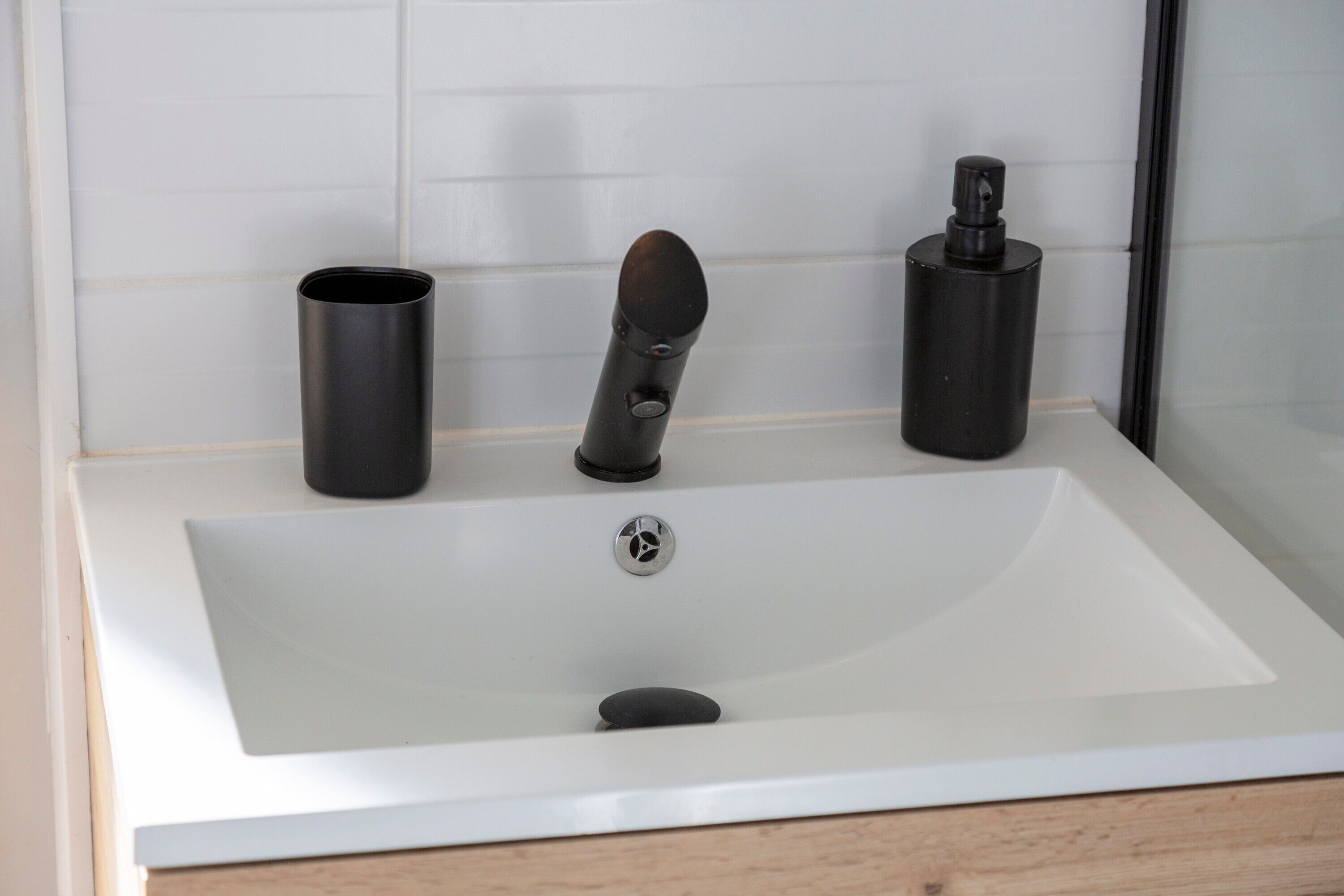 Un bagno con un lavandino bianco, un rubinetto e un erogatore di sapone.