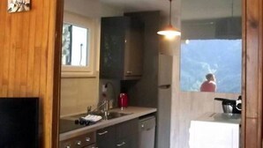 Une cuisine compacte avec des meubles de rangement en bois, un évier, un four à micro-ondes et une fenêtre donnant sur un beau paysage.