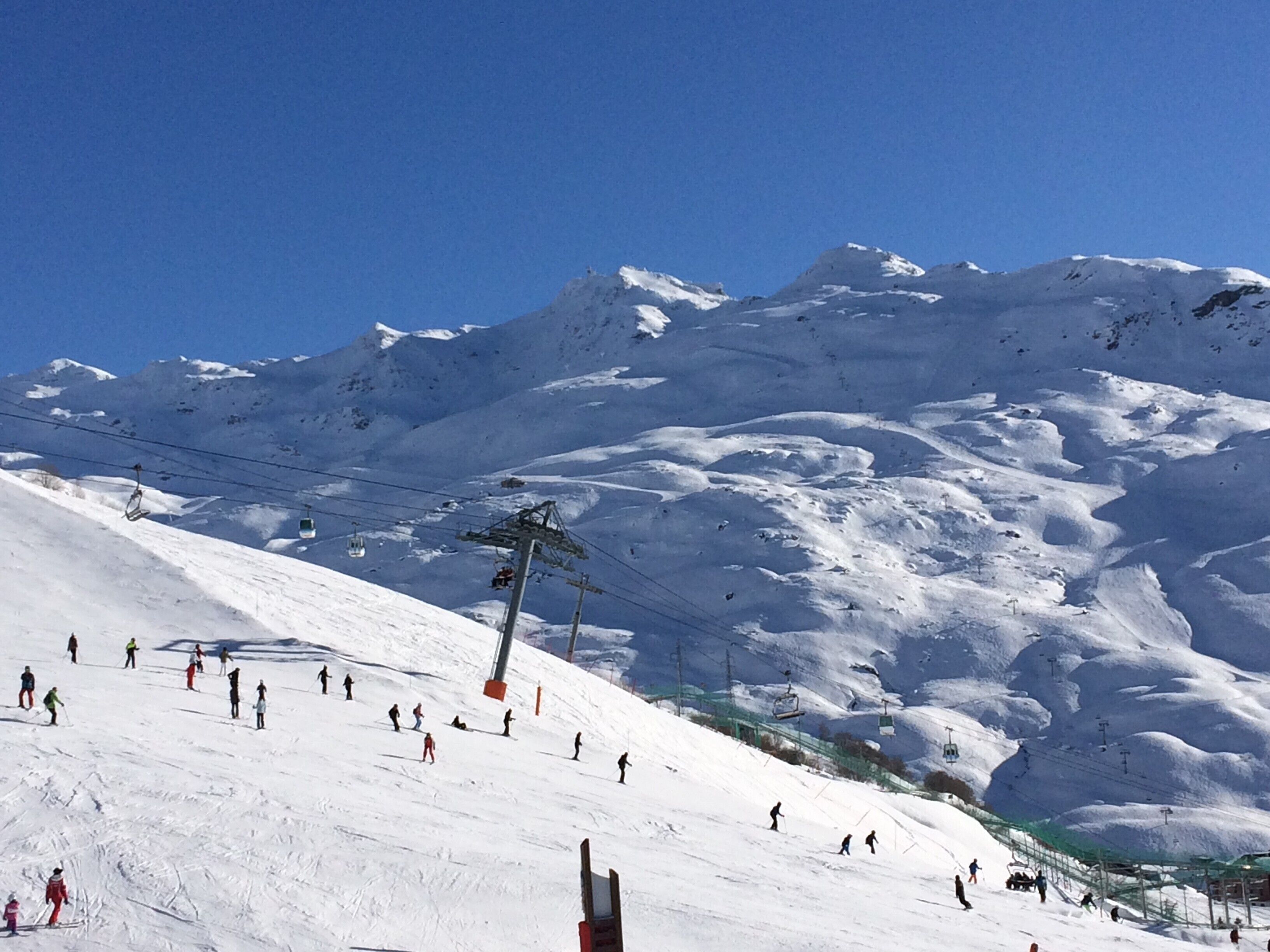 A snowy ski slope with skiers and a ski lift.