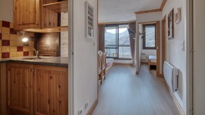 Una cocina con armarios de madera, un lavabo y una ventana con vistas a montañas.