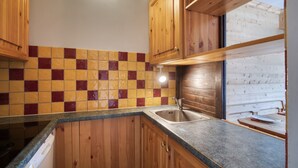 Una cocina con armarios de madera, salpicadero de azulejos y una ventana.