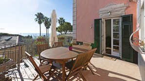 A patio with a round wooden table and chairs, a potted plant, and a view of the sea. - Villino Rosanna with Private Pool and Sea View (Bogliasco)