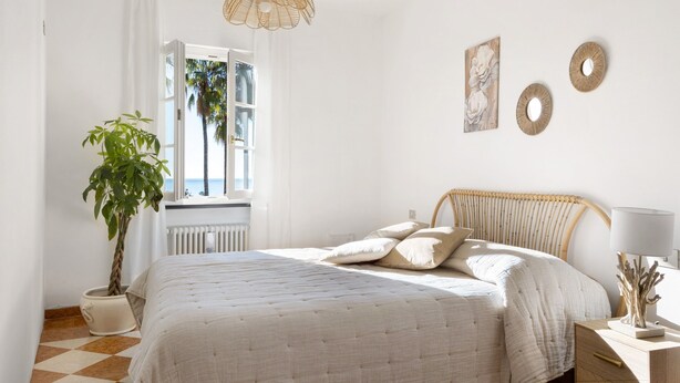 A bedroom with a bed, a potted plant, a window with curtains, and wall decor. - Villino Rosanna with Private Pool and Sea View (Bogliasco)