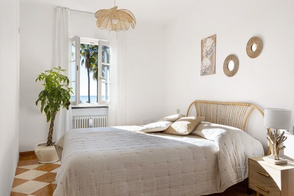 Une chambre à coucher avec un lit, une plante en pot, une fenêtre avec des rideaux et des éléments de décoration murale.
