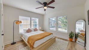 A bedroom with a bed, a ceiling fan, a floor lamp, and a potted plant. - Trendy Boho Stay - Pergola • Pool • Fire Pit (Houston)