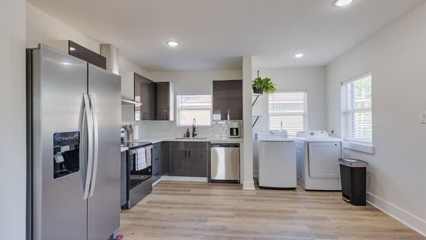A modern kitchen with stainless steel appliances, a dishwasher, and a washing machine. - Trendy Boho Stay - Pergola • Pool • Fire Pit (Houston)