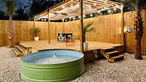 A backyard with a wooden pergola, a hot tub, and a seating area with chairs and tables. - Trendy Boho Stay - Pergola • Pool • Fire Pit (Houston)