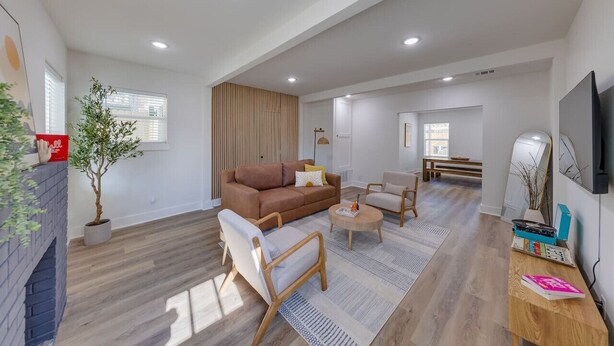 Un salon spacieux avec un canapé marron, une table basse en bois et un téléviseur fixé au mur.