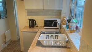 A compact kitchen with white cabinets, a microwave, a kettle, and a sink. - Perfect 2-bedroom house, Albert cottage with WiFi in charming Southampton (Southampton)