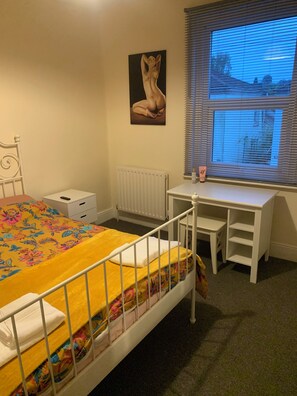 A bedroom with a bed, a desk, a radiator, and a window with blinds. - Perfect 2-bedroom house, Albert cottage with WiFi in charming Southampton (Southampton)